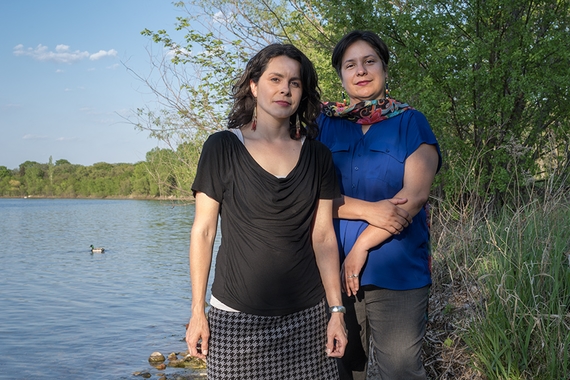 Two women stand beside lake Bde Maka Ska