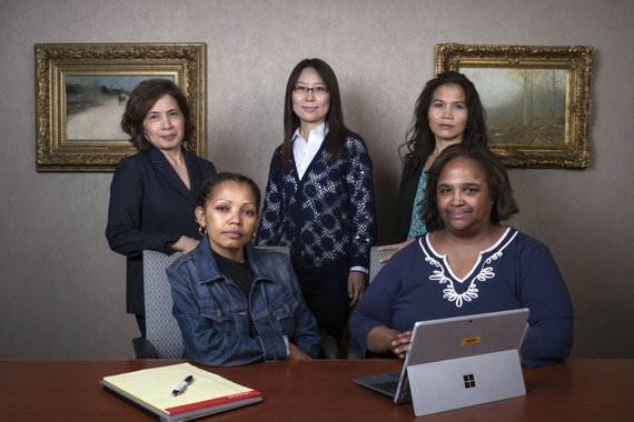 Laura Dawis, Eman Ausman, Hongna Bystrom, Tola Ou-Quinlan, and Rochelle M. Emmel sitting/standing behind a desk with office materials in front of them