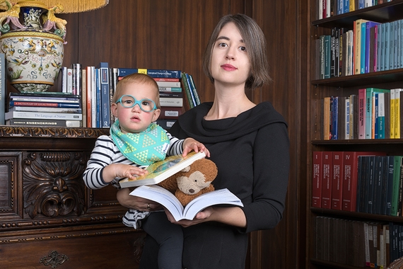 A faculty member holds her daughter while reading in Upson library.