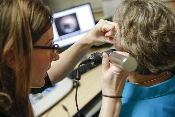 A person giving another person an ear scope examination
