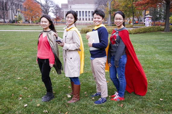 Group of four STATCOM students posing on Northrop Mall wearing superhero capes