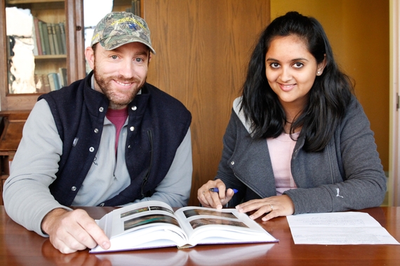 Two MGIS students sitting together at a table. They are looking at the camera and smiling.