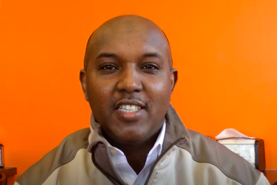 Abdirahman smiling in front of an orange wall