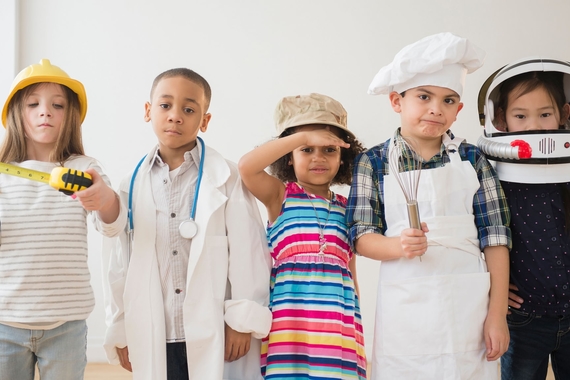 a group of children dressed in costumes of job occupations (A builder, a doctor, a chef, and an astronaut)