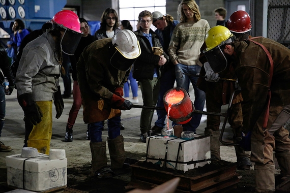 Foundry students pouring melted aluminum into some molds while a group of people watch