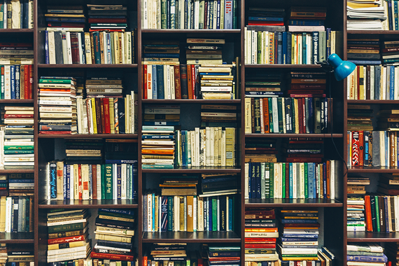 Photo of books stacked and lined up on bookshelves