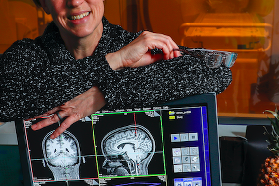 Cheryl Olman leaning on a computer screen showing brain scans