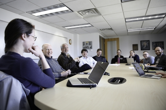 Students and faculty gather for a discussion around a large conference table
