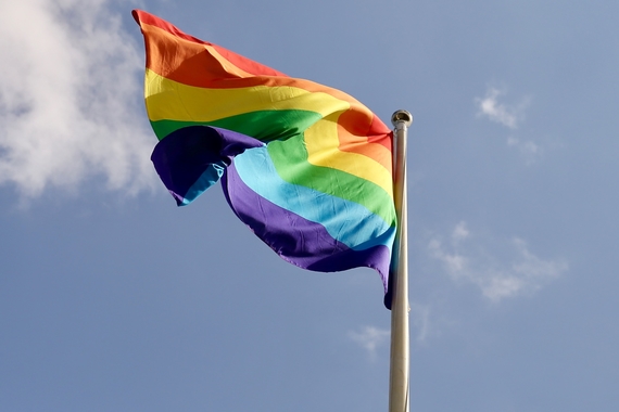 Flag with rainbow colors waving in sky