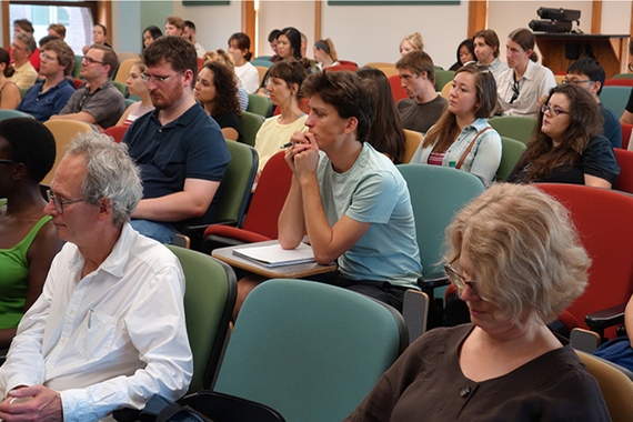 Students and researchers in a large classroom with multi-colored seats