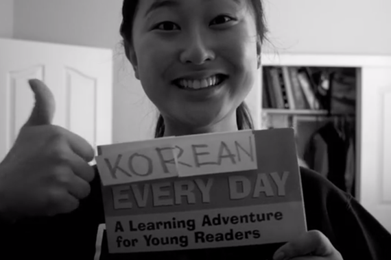 Jennie with a sign that says "Korean Every Day. A Learning Adventure for Young Readers"