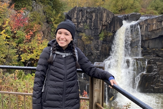 Julia Fultz-Flores with autumn trees and a waterfall in the background