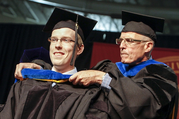 Graduate student Keaton Miller being hooded at a commencement ceremony