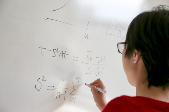 Statistics grad student writing formula on white board