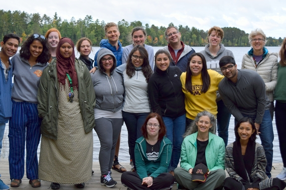 a group of students and faculty stand in front of a lake