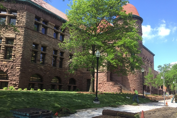 Photo of outside of Pillsbury Hall with green sod installed; yellow sandstone building with red roof and turret