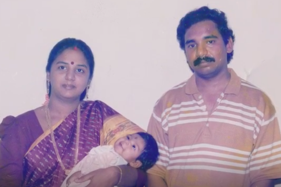 Renita as a baby being held by her mother who is standing next to her father