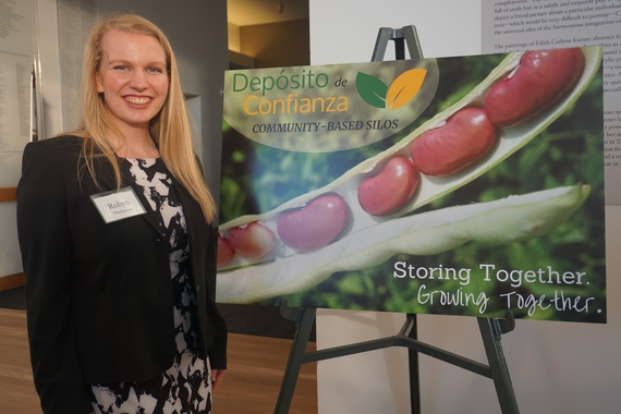 CLA sophomore Robyn Thompson smiling next to a poster for her project about community-based silos