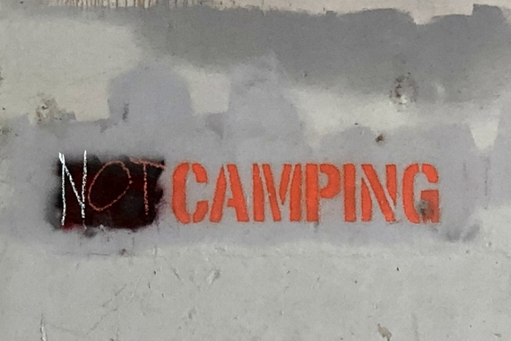 Concrete wall with graffiti that reads "Not Camping"