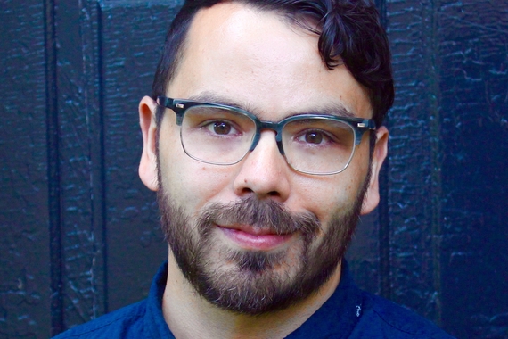Jason Ruiz, a person with dark brown hair, glasses, and a beard and mustache, wearing a buttoned shirt