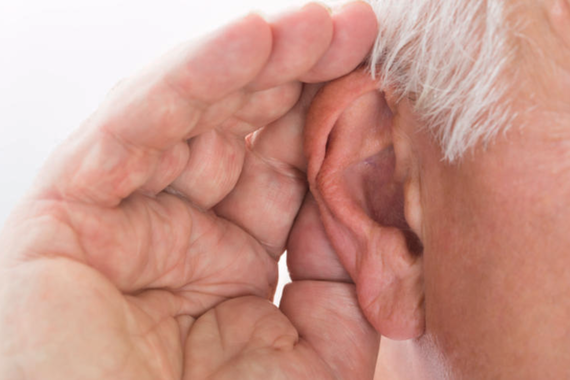 a hand being held up to a person's ear - the person has white hair