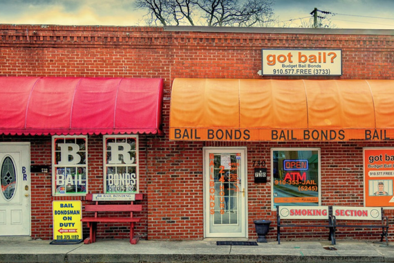 shot from a street, a brick building covered in sign that say "BAIL BONDS" and "got bail?"