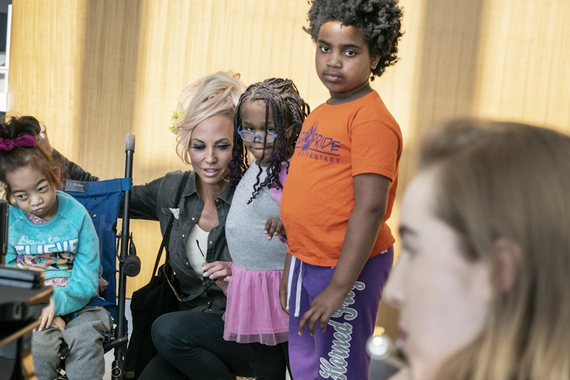 A mother and her three children watch as Megan Reich plays the flute in the lobby of the hospital