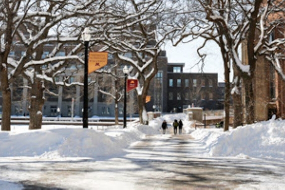 Sunny winter scene from Northrop Mall looking toward Coffman Union. A few students are walking on the sidewalk