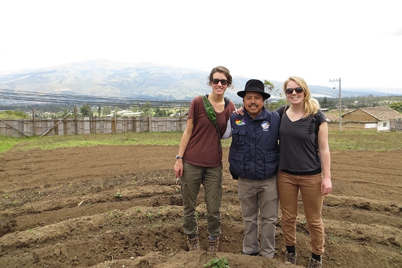 Two female University of Minnesota students standing in a field with an Ecuadoran man