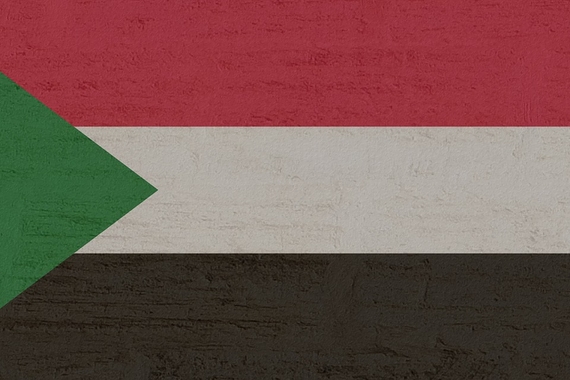 Flag of Sudan, a horizontal tricolor of red, white, and black stripes with a green triangle based at the hoist. 