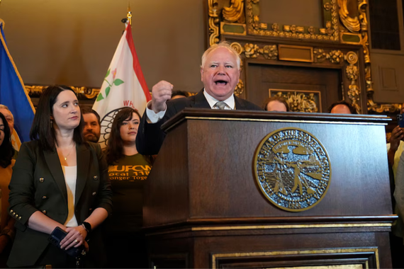 Walz stands behind a podium, delivering an address