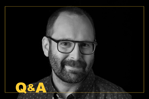 Smiling bearded man against black with yellow "Q&A"