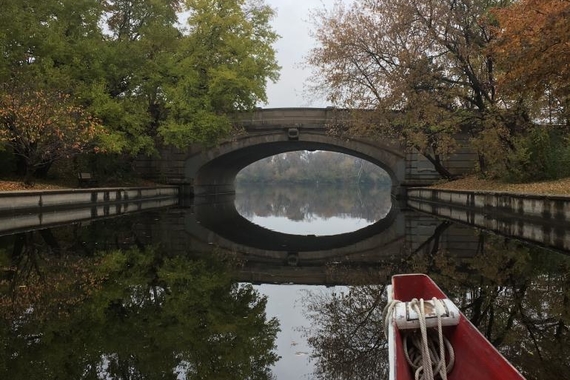 Photo of a small bridge over still water taken from a canoe