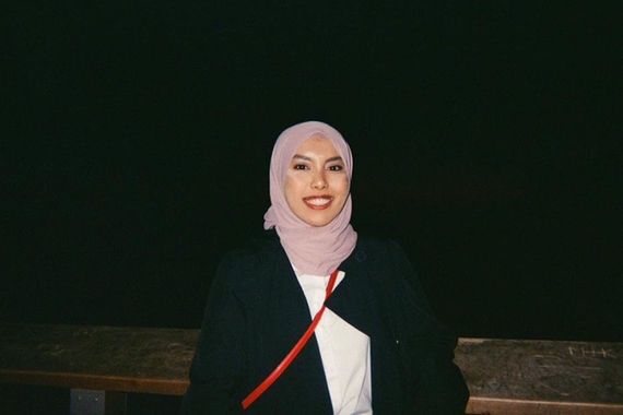 Young woman of color wearing a pink hijab and black coat