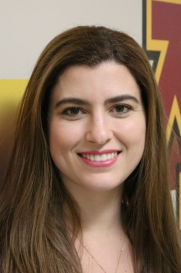 Headshot of Carolina Velloso in front of a wall with the UMN logo