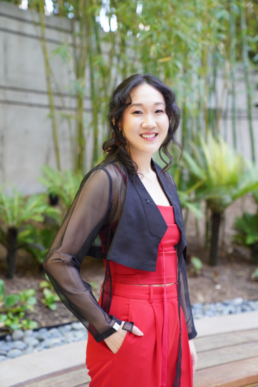 Naomi Ko standing outside in a red dress and black jacket