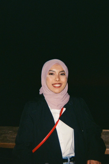 Yasmeen Iman Junaidi Jaafar wearing a light purple hijab and a black coat, standing outside at night