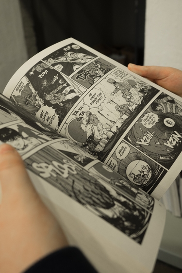 Two hands holding open a black and white graphic novel