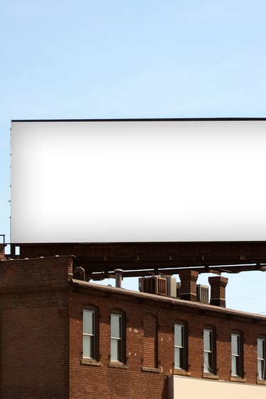A large, blank billboard on the roof of a large brick building