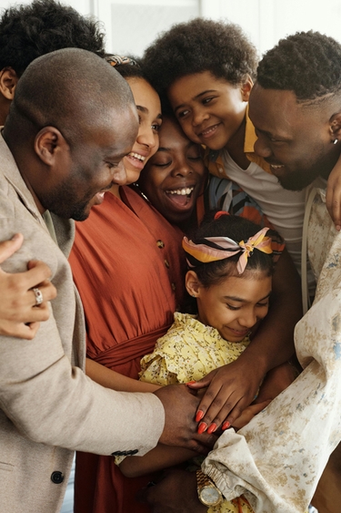 A family of several people of color exchange a group hug