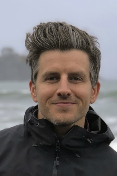 Headshot of Paul Anheier standing near the ocean