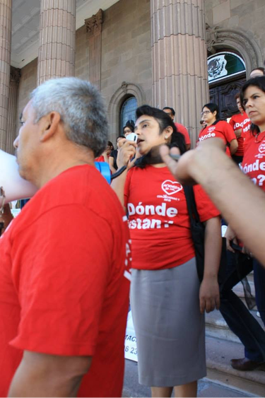 small group of adults wearing red shirts and speaking into a megaphone