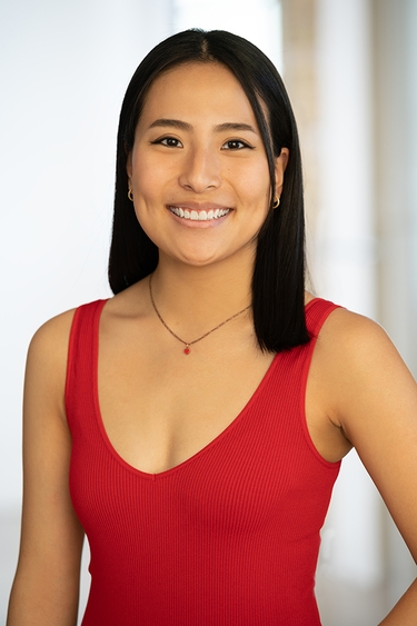 Female Actor wearing a red tank, looking into camera confidently with a smile.