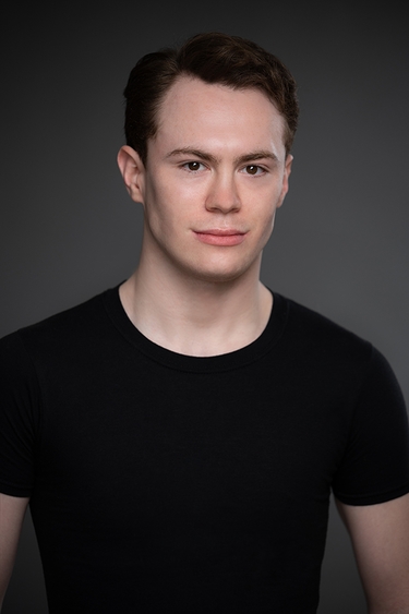 Male Actor in a black t-shirt looking into camera confidently.