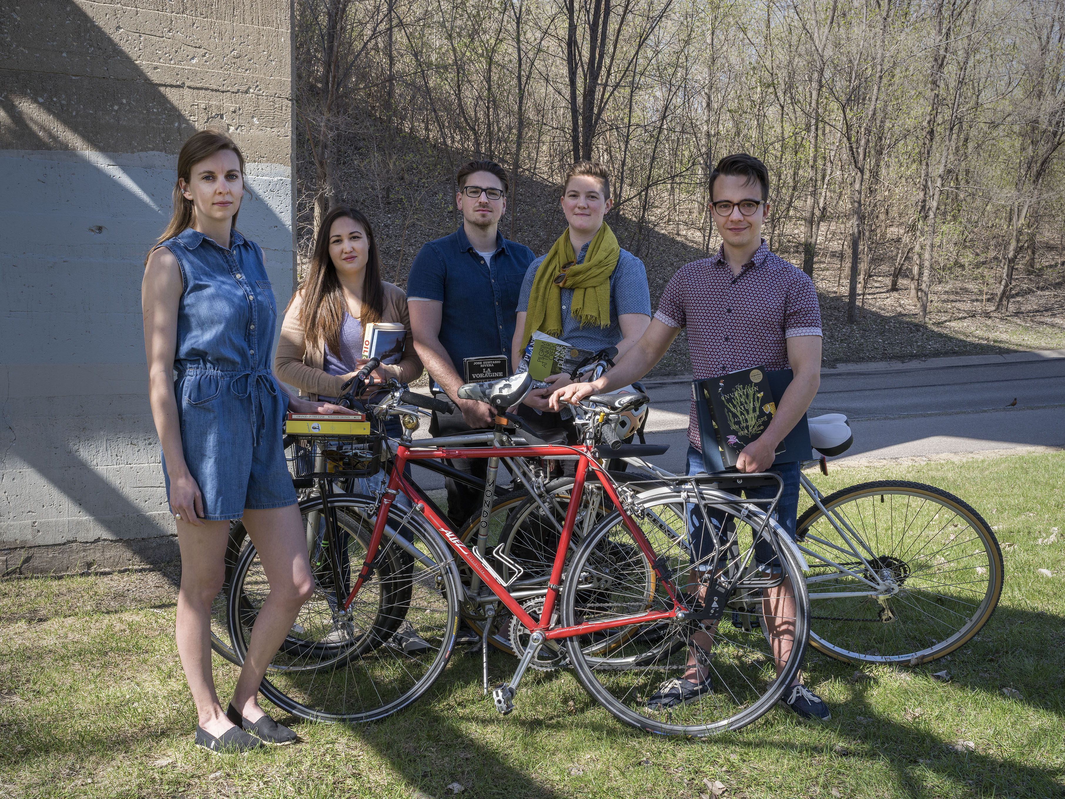 Five graduate students gather around bikes down by the Mississippi river.