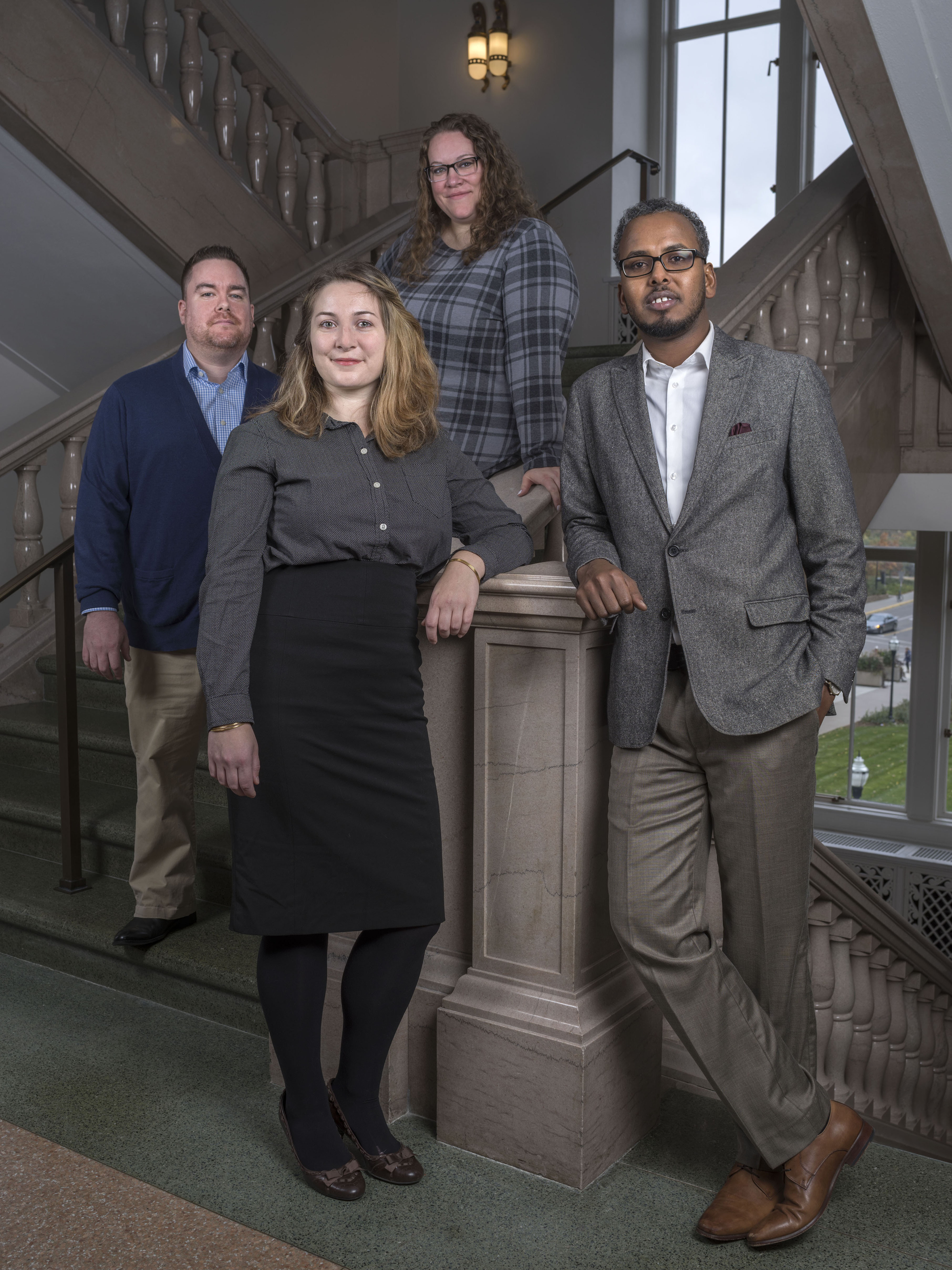 Four Alumni stand in business attire on the interior steps at Northrup hall.