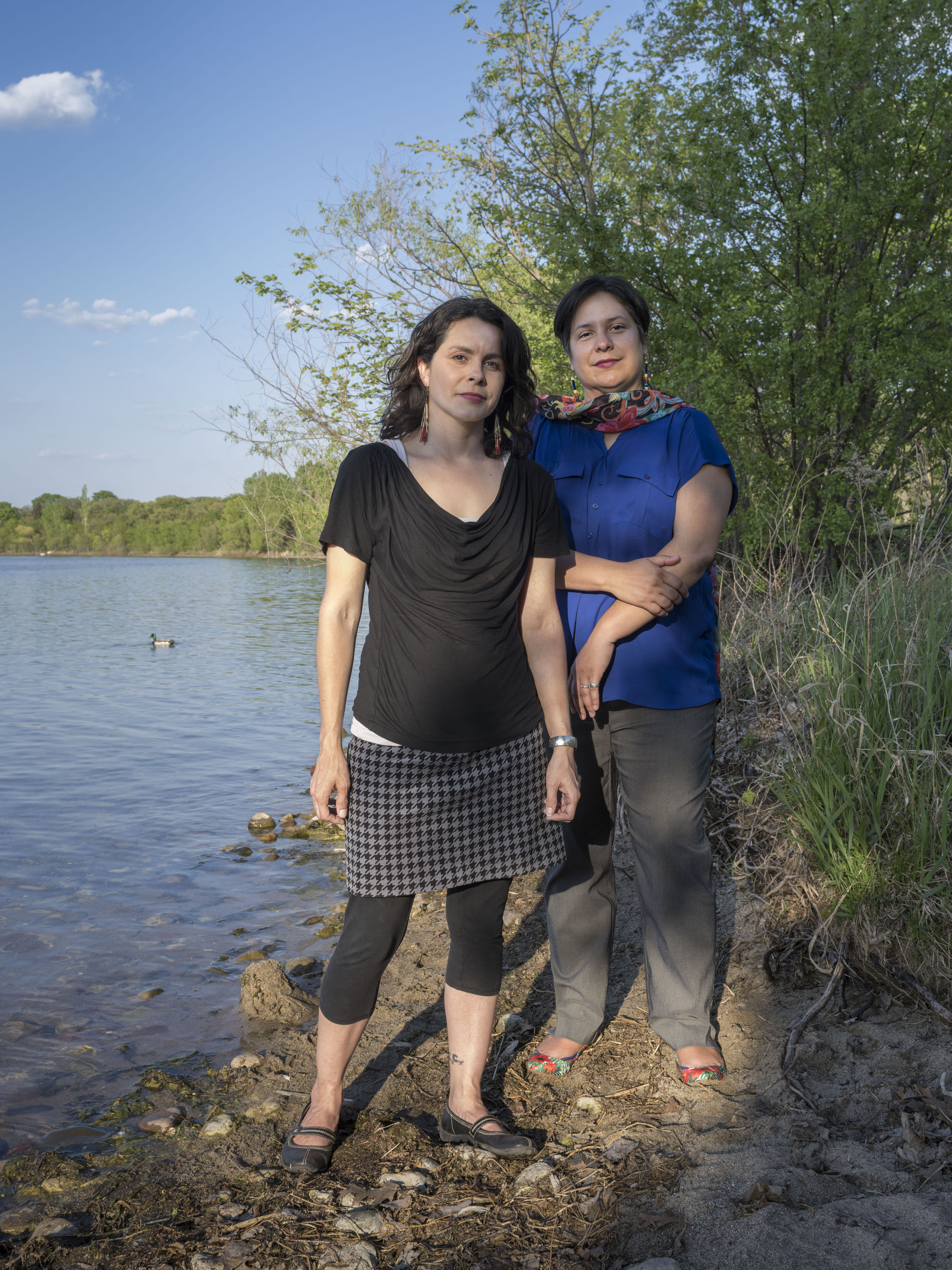 Two women stand beside lake Bde Maka Ska