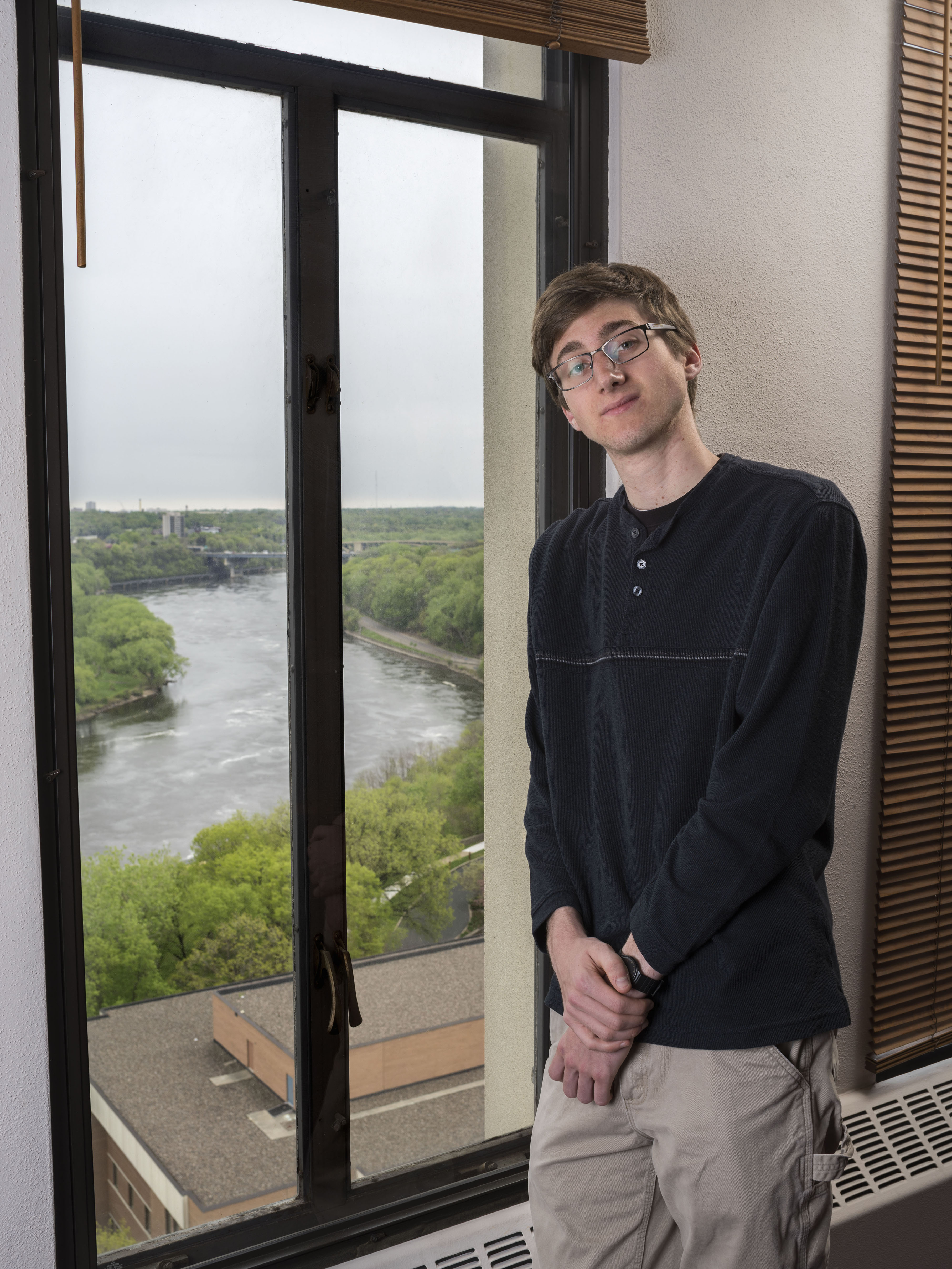 A student leans against a window that overlooks the Mississippi river.