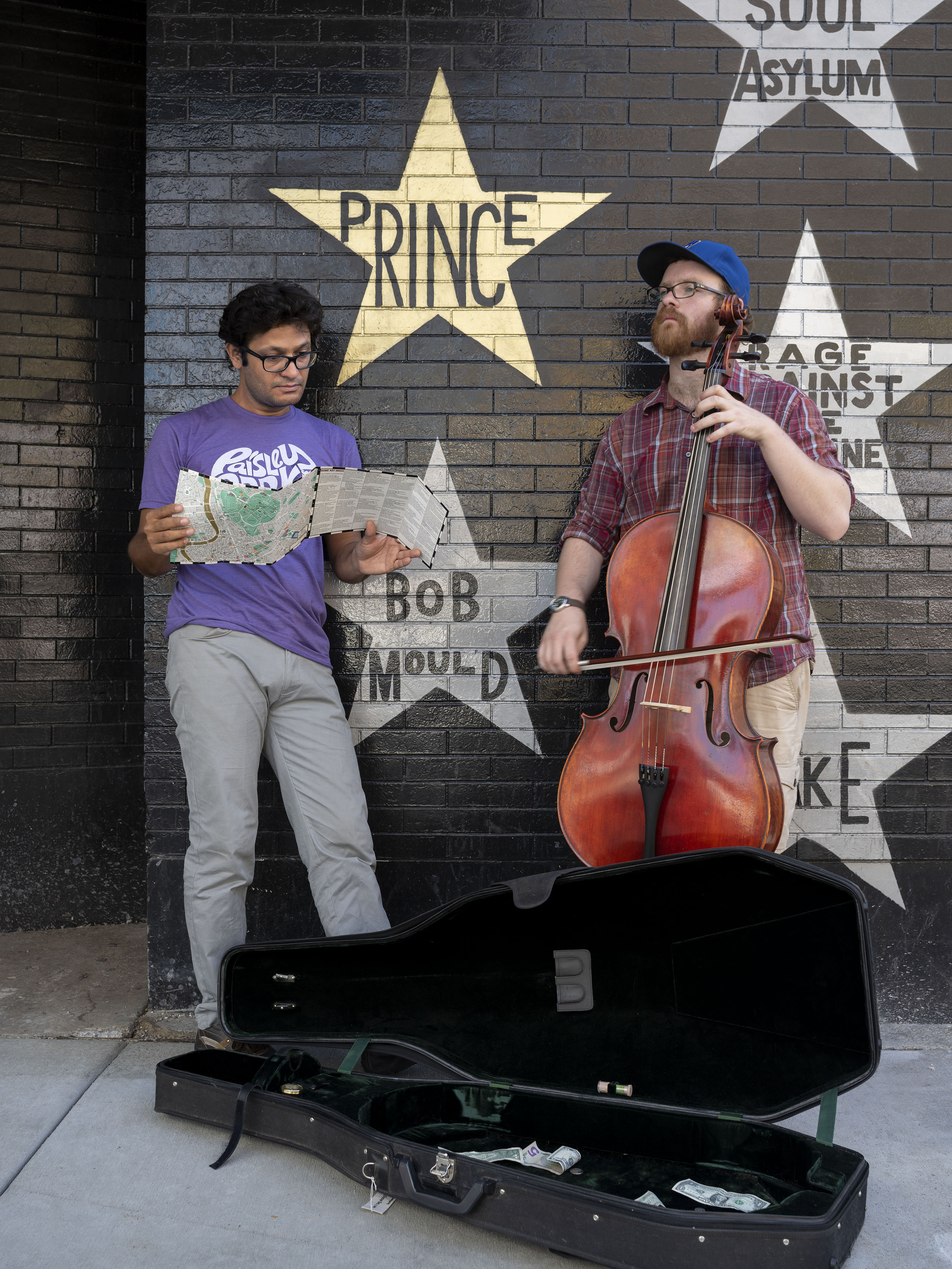 A man leans on First Avenue club wall near the prince star, while a student plays the cello.