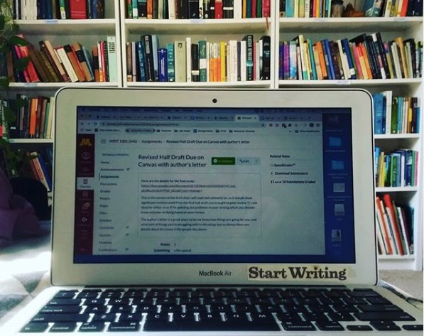 Photo of PhD candidate Clara Biesel's office with a wall of books and sticker on computer "Start Writing"